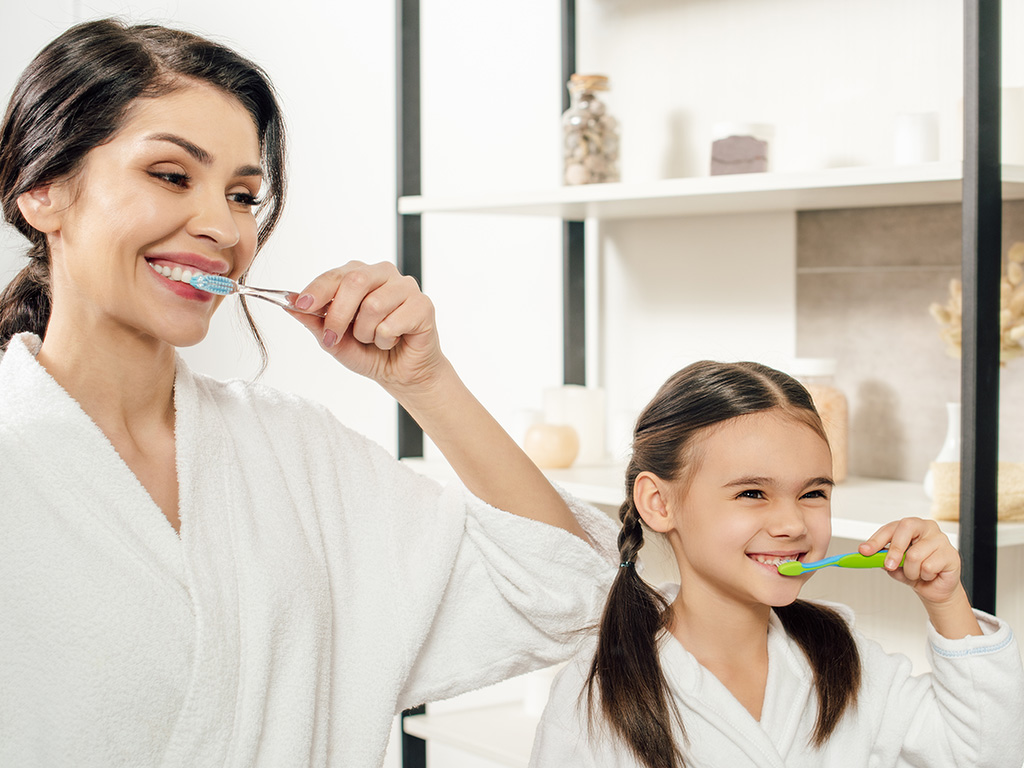 mother-and-daughter-brushing-teeth-in-bathroom